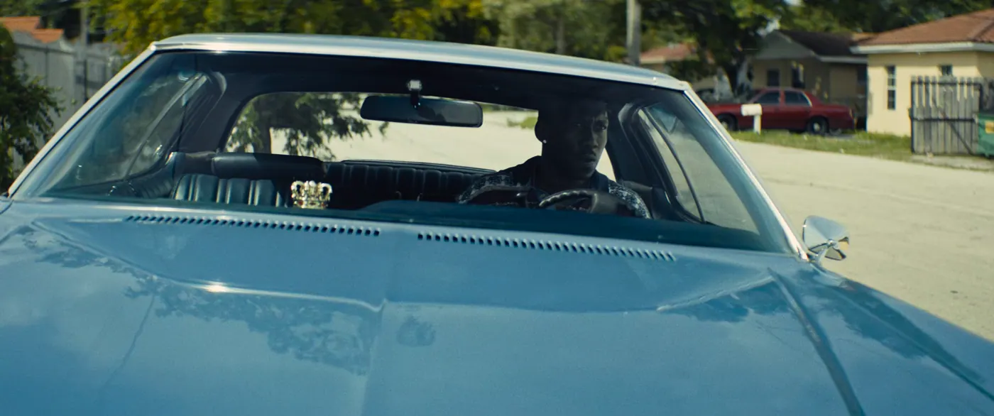Moonlight (2016), Barry Jenkins — plan moyen, jour, extérieur, un personnage : rue, voiture, couronne, volant, rétroviseur, maison, conduire
