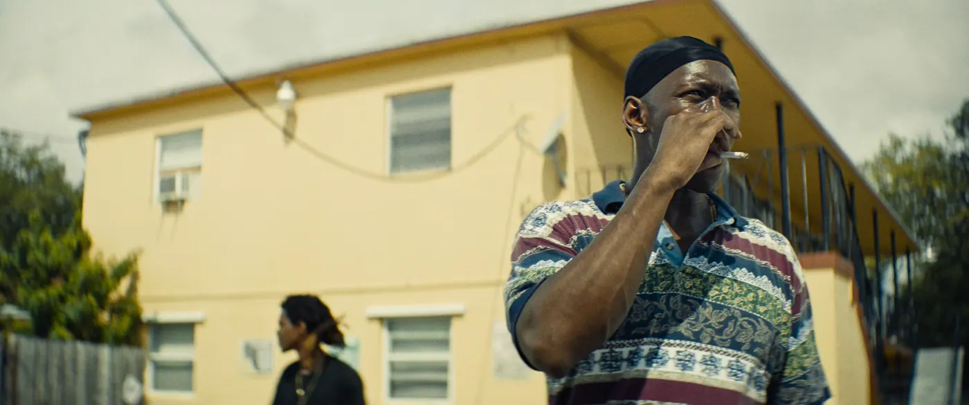 Moonlight (2016), Barry Jenkins — plan rapproché, jour, extérieur, deux personnages : rue, cigarette, immeuble, climatiseur, fil électrique, durag, polo, fumer