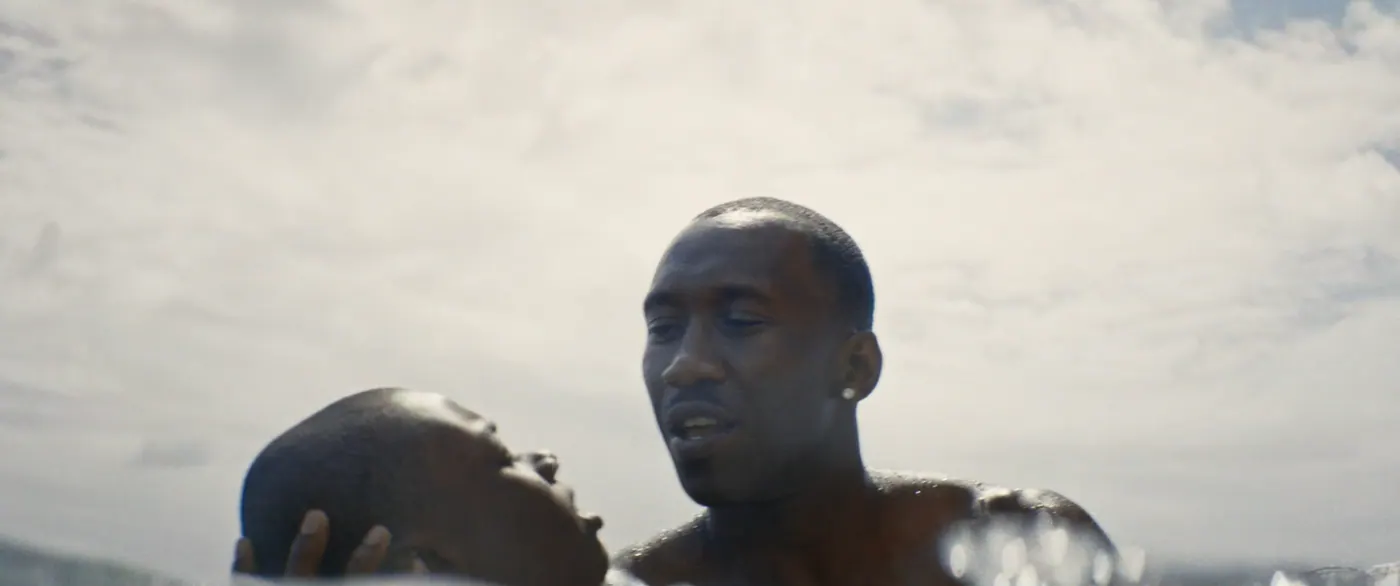 Moonlight (2016), Barry Jenkins — plan rapproché, jour, extérieur, deux personnages : mer, boucle d’oreille, nuage, torse nu, nager
