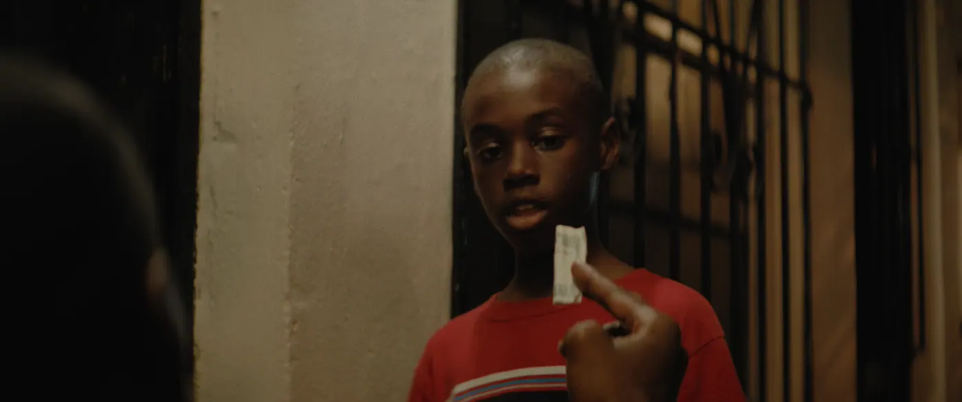 Moonlight (2016), Barry Jenkins — plan rapproché, nuit, deux personnages, lumière chaude, clair-obscur : tee-shirt rouge, billet, grille