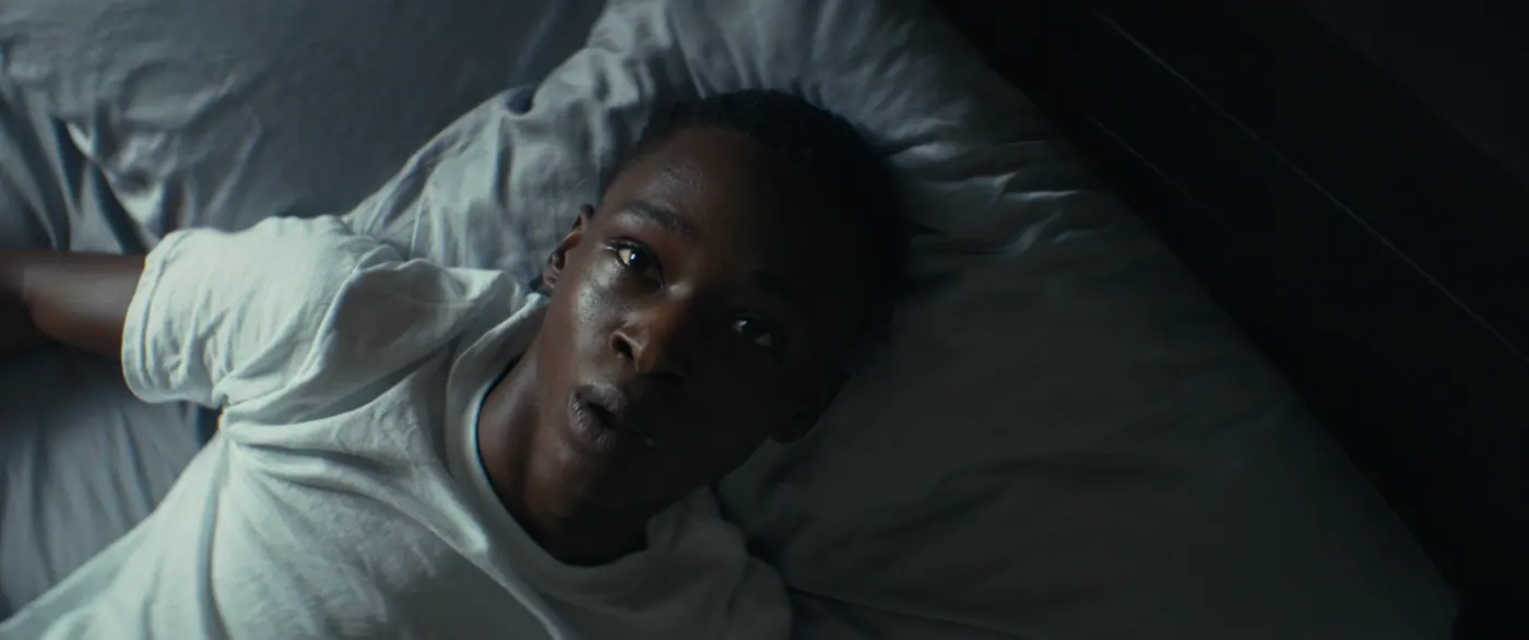 Moonlight (2016), Barry Jenkins — plan rapproché, intérieur, un personnage, lumière froide : chambre, tee-shirt blanc, lit, oreiller, drap