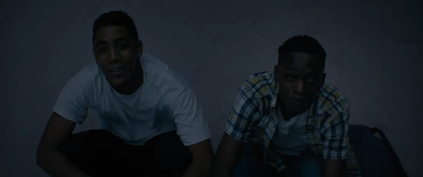 Moonlight (2016), Barry Jenkins — plan moyen, nuit, extérieur, deux personnages, lumière froide : plage, tee-shirt blanc, sac à dos, collier, boucle d’oreille, chemise à carreaux