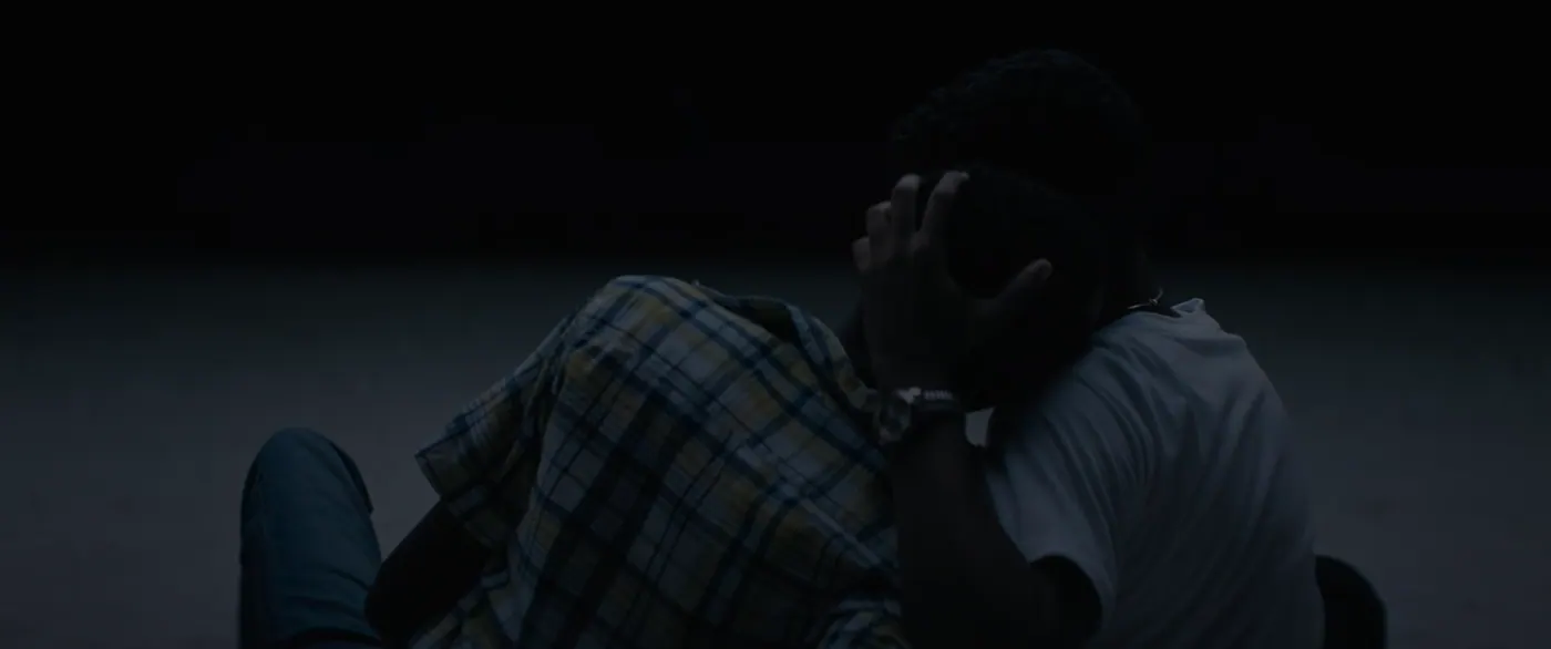 Moonlight (2016), Barry Jenkins — plan rapproché, nuit, extérieur, deux personnages, lumière froide : plage, tee-shirt blanc, montre, chemise à carreaux, jean, s’embrasser