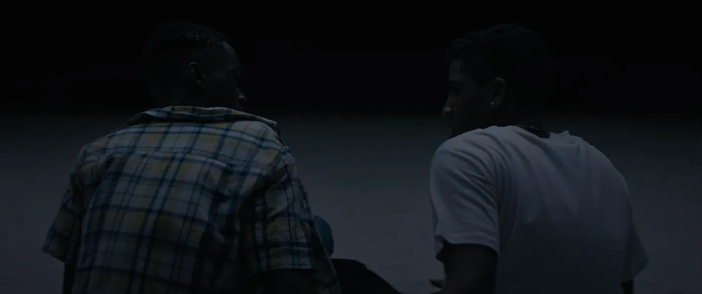 Moonlight (2016), Barry Jenkins — plan rapproché, nuit, extérieur, deux personnages, lumière froide : plage, tee-shirt blanc, boucle d’oreille, chemise à carreaux