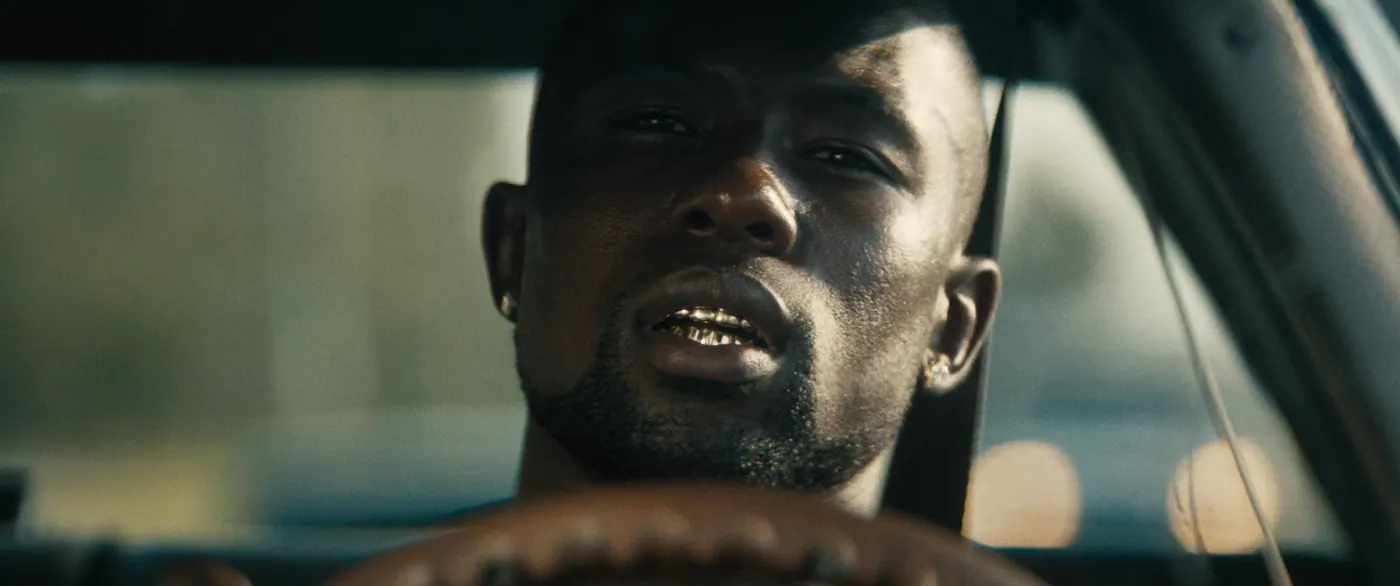 Moonlight (2016), Barry Jenkins — gros plan, jour, intérieur, un personnage : voiture (habitacle), voiture, volant, grillz, dents en or, boucle d’oreille, conduire