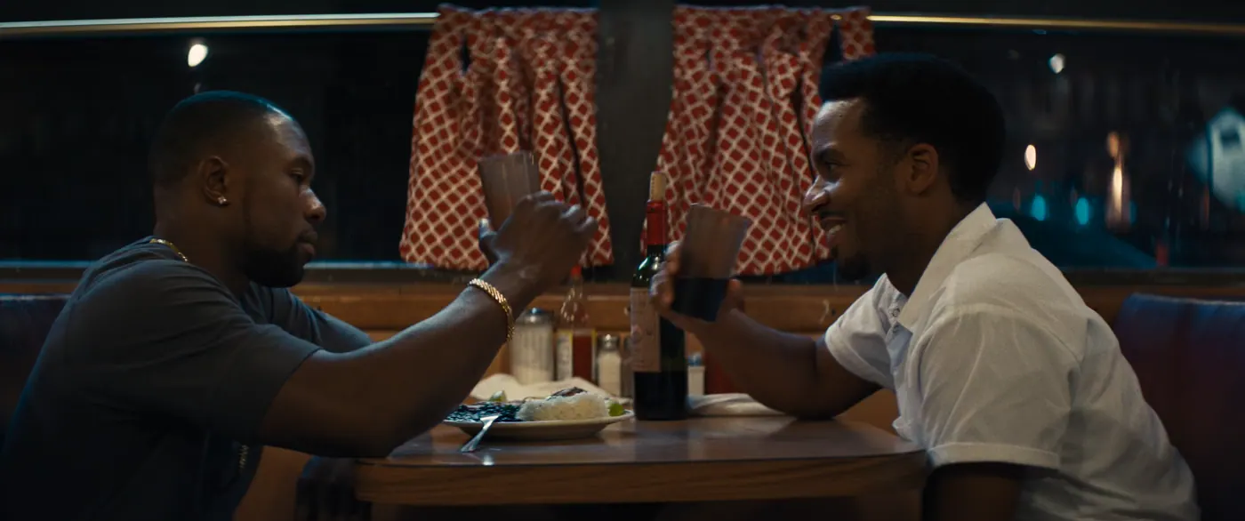 Moonlight (2016), Barry Jenkins — plan moyen, nuit, intérieur, deux personnages, lumière chaude : restaurant, chemise blanche, bouteille de vin, verre, assiette, fourchette, riz, tee-shirt