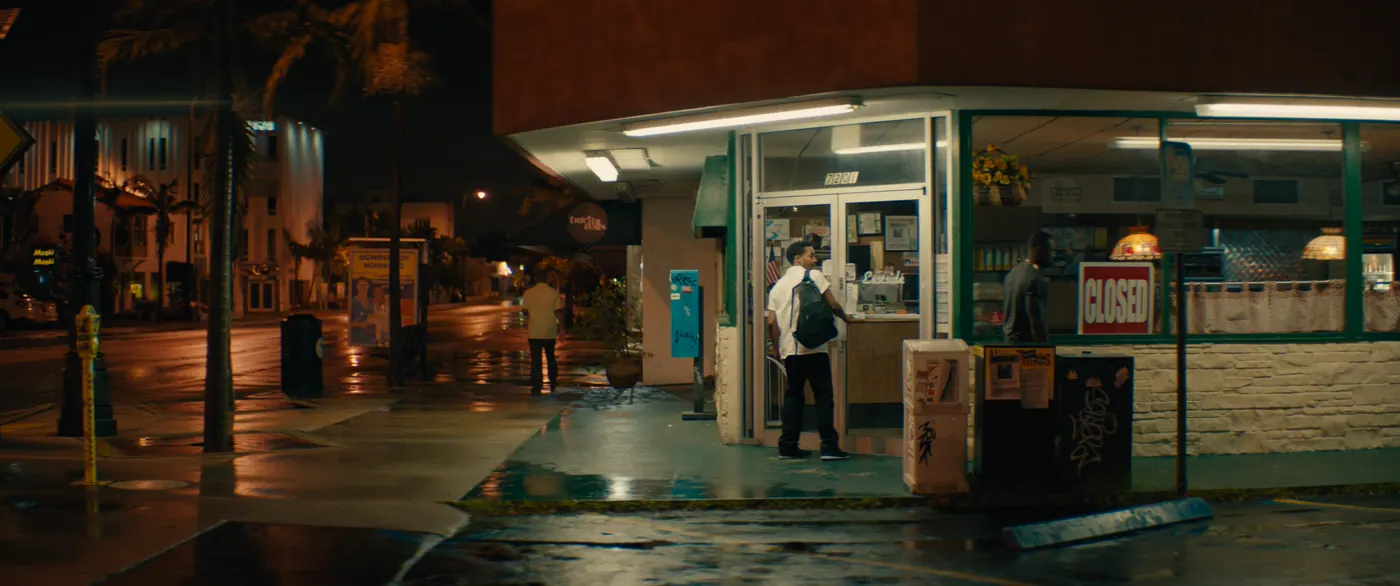 Moonlight (2016), Barry Jenkins — plan d’ensemble, nuit, extérieur, trois personnages, néon, lumière froide : restaurant, rue, chemise blanche, enseigne, pancarte, néon, palmier, parcmètre