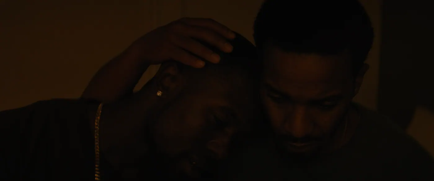 Moonlight (2016), Barry Jenkins — gros plan, nuit, intérieur, deux personnages, clair-obscur, lumière chaude : chaîne en or, boucle d’oreille, tee-shirt, s’enlacer