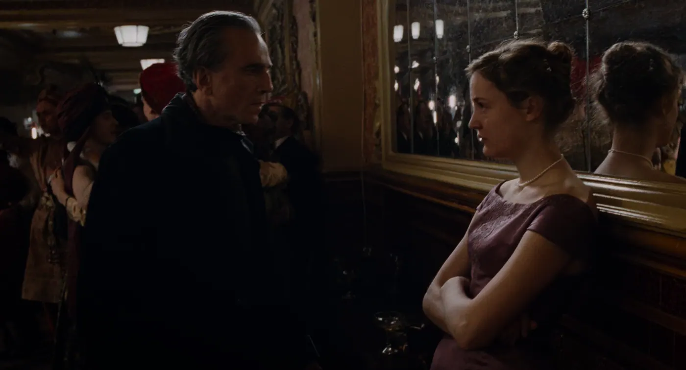 Phantom Thread (2017), Paul Thomas Anderson — plan rapproché, intérieur, foule, lumière chaude, clair-obscur : salle de bal, manteau noir, robe bordeaux, miroir, collier de perles