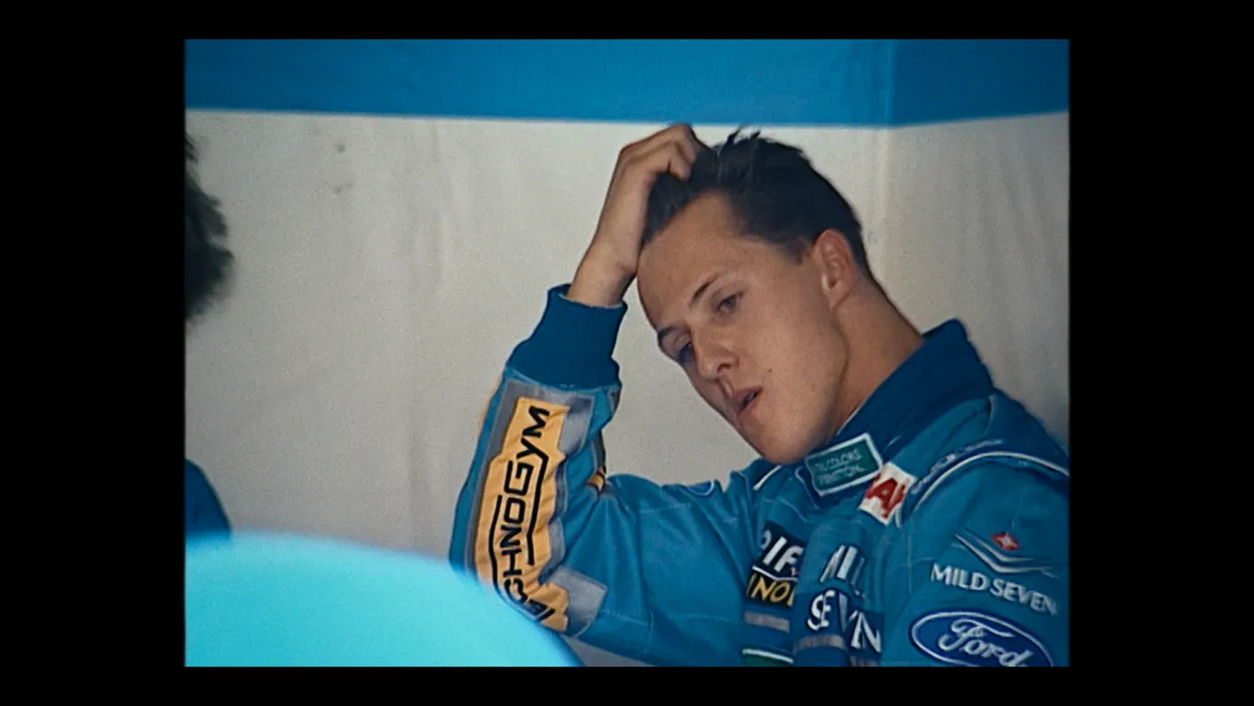 Schumacher ’94 — The Birth of a Legend (2026), Christin Freitag — plan rapproché, intérieur, deux personnages : garage, combinaison bleue, combinaison de pilote