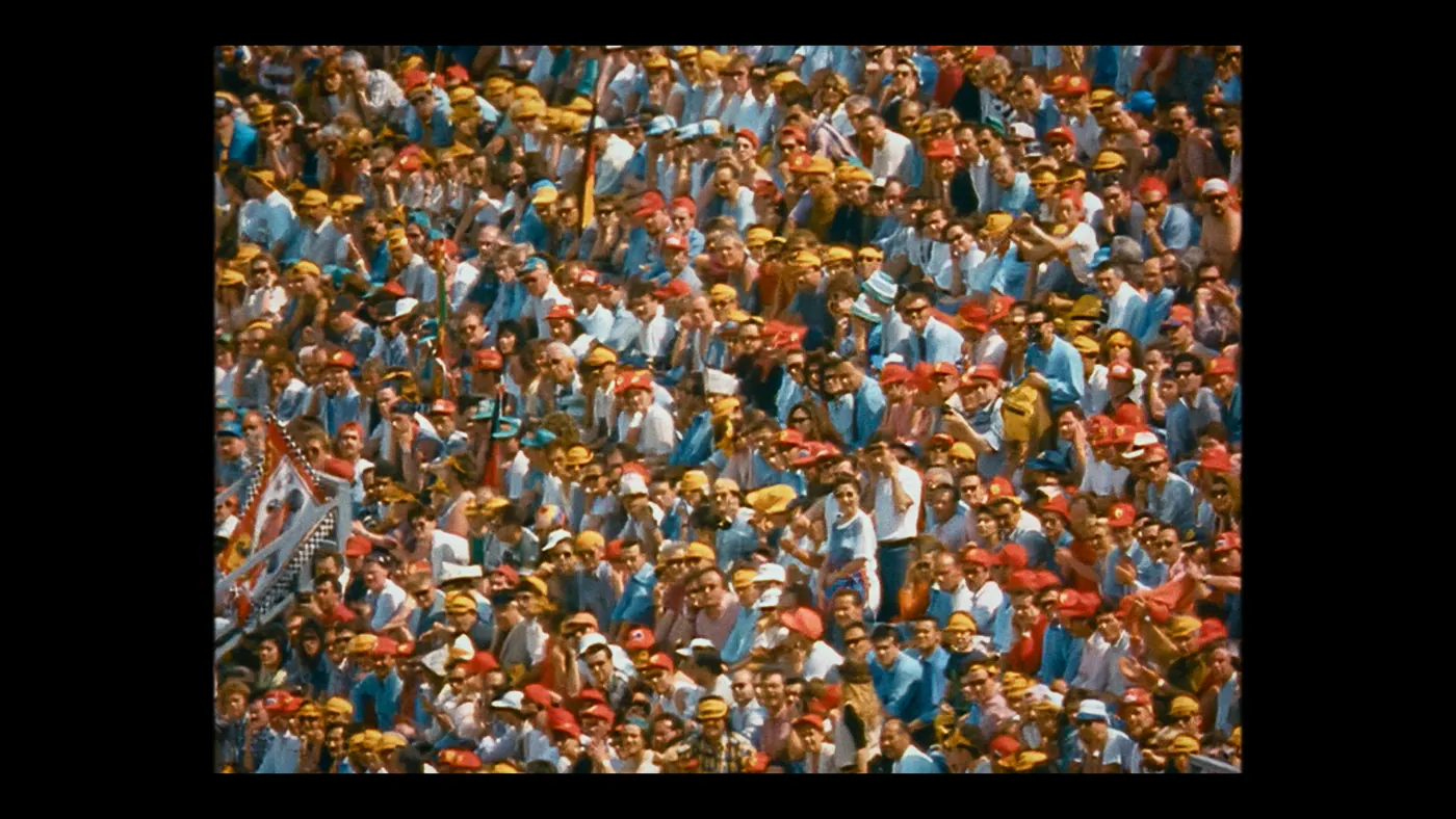 Schumacher ’94 — The Birth of a Legend (2026), Christin Freitag — plan d’ensemble, jour, extérieur, foule : tribune, drapeau, casquette