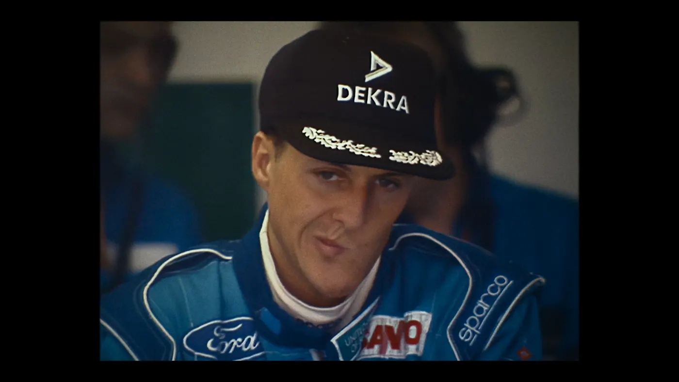 Schumacher ’94 — The Birth of a Legend (2026), Christin Freitag — plan rapproché, trois personnages : casquette noire, combinaison bleue, combinaison de pilote