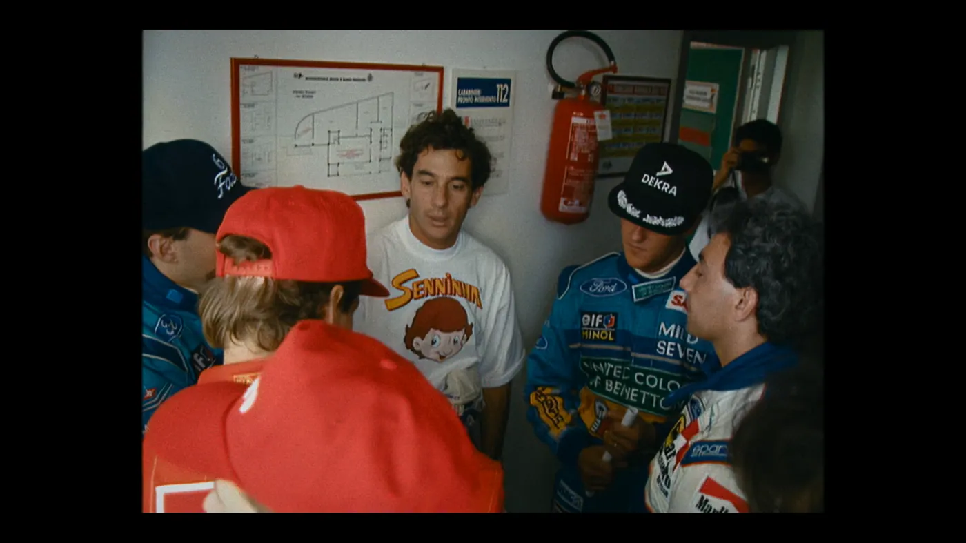 Schumacher ’94 — The Birth of a Legend (2026), Christin Freitag — plan rapproché, intérieur, foule : casquette rouge, casquette noire, extincteur, plan d’évacuation, appareil photo