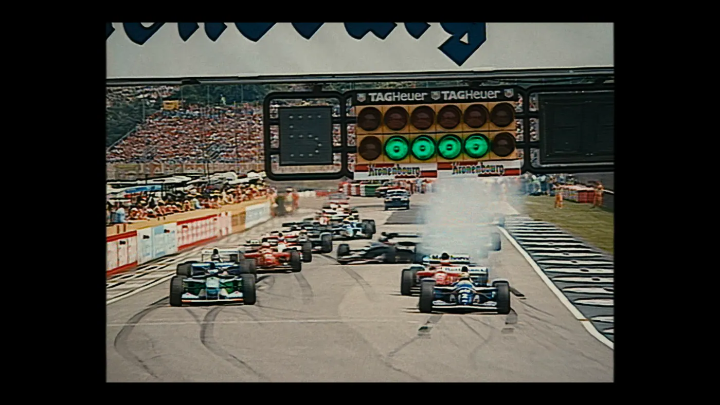 Schumacher ’94 — The Birth of a Legend (2026), Christin Freitag — plan d’ensemble, jour, extérieur, foule : circuit automobile, grille de départ, voiture de course, formule 1, feu de départ