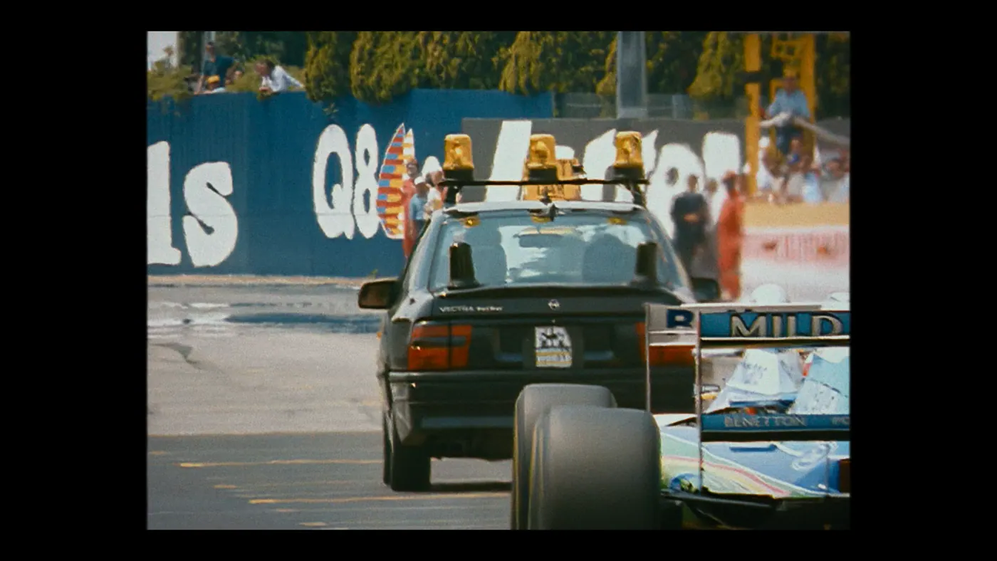 Schumacher ’94 — The Birth of a Legend (2026), Christin Freitag — plan large, jour, extérieur, foule, soleil direct : circuit automobile, voiture de sécurité, voiture, opel vectra, gyrophare