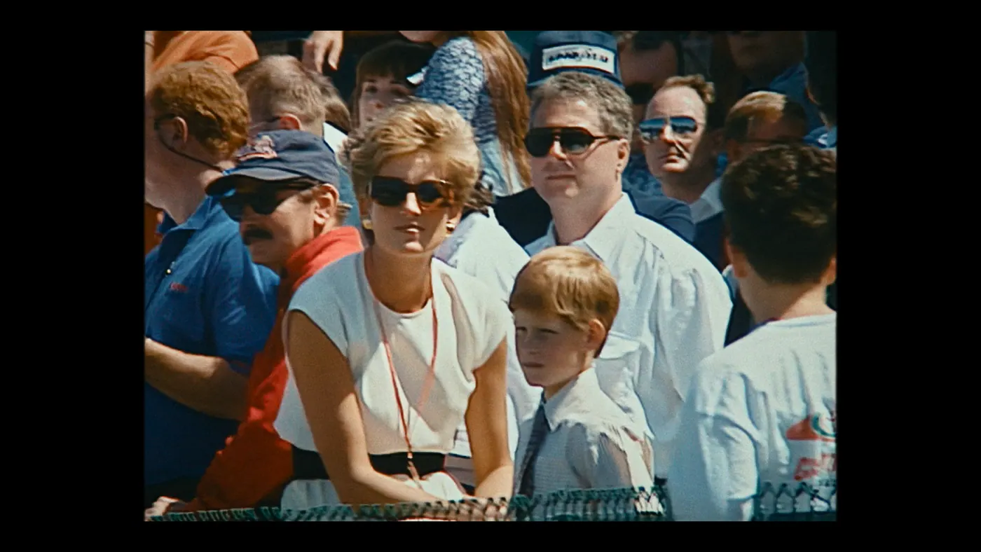 Schumacher ’94 — The Birth of a Legend (2026), Christin Freitag — plan rapproché, jour, extérieur, foule, soleil direct : tribune, grillage, lunettes de soleil, cravate
