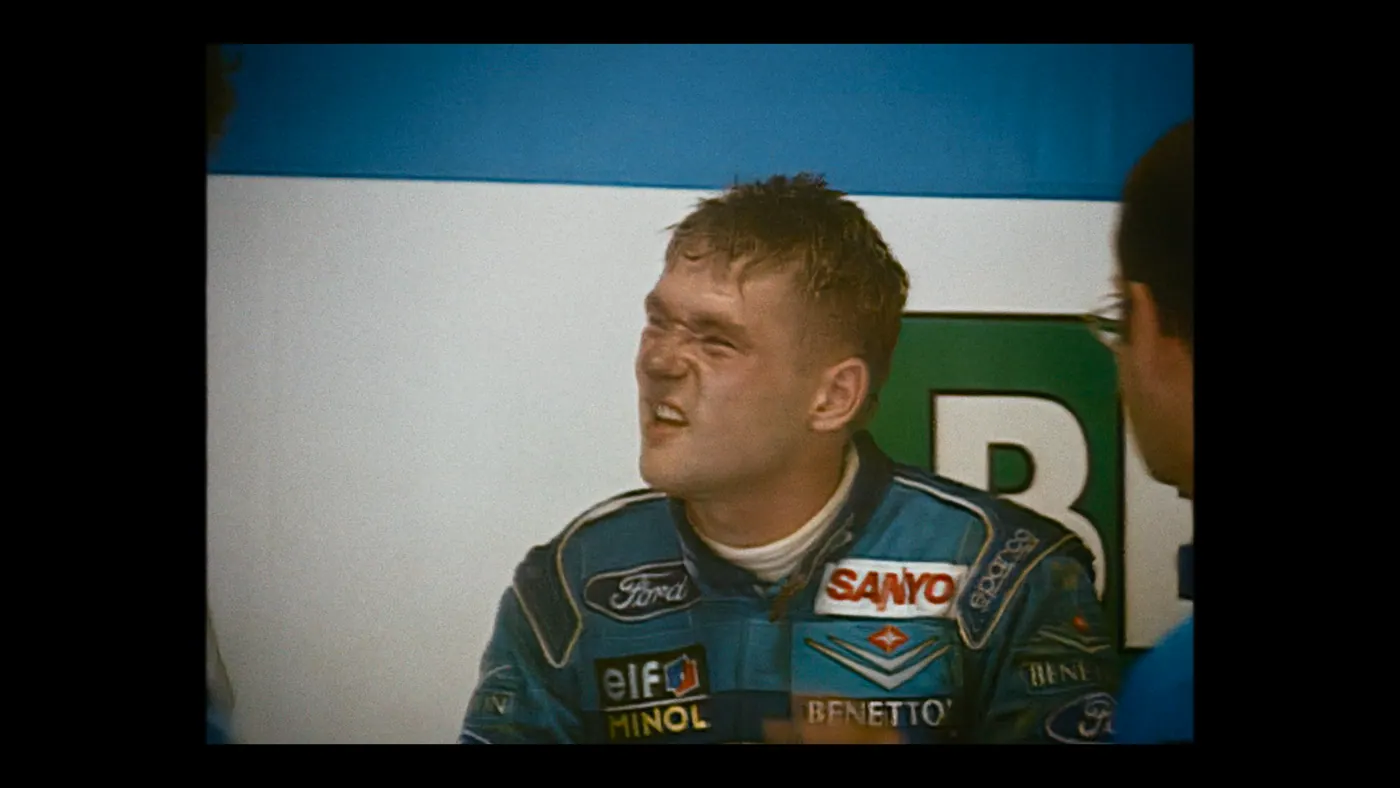 Schumacher ’94 — The Birth of a Legend (2026), Christin Freitag — plan rapproché, jour, deux personnages : combinaison bleue, combinaison de pilote, lunettes