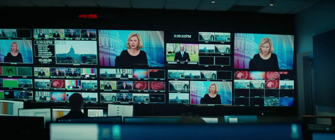 Vice (2018), Adam McKay — plan large, intérieur, un personnage, éclairage coloré, lumière froide : studio de télévision, mur d’écrans, téléviseur, écran d’ordinateur, horloge numérique